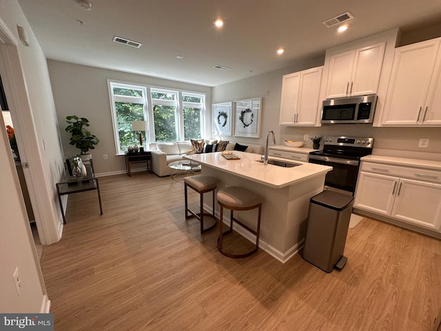 kitchen featuring a center island with sink, appliances with stainless steel finishes, and white cabinets