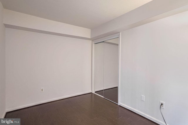 unfurnished bedroom featuring a closet and dark hardwood / wood-style flooring