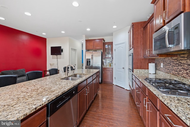 kitchen with decorative backsplash, sink, light stone countertops, appliances with stainless steel finishes, and dark hardwood / wood-style flooring