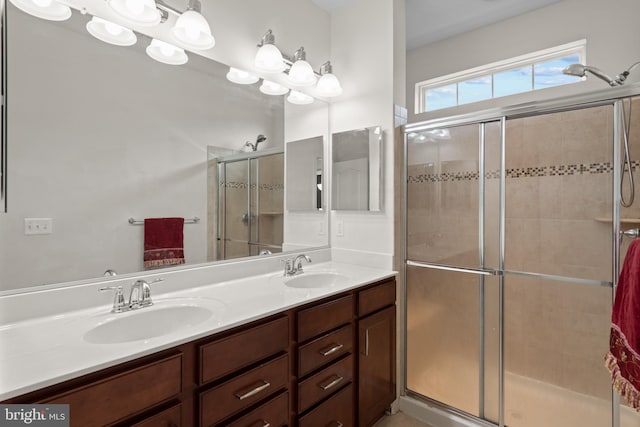 bathroom featuring a shower with door and vanity