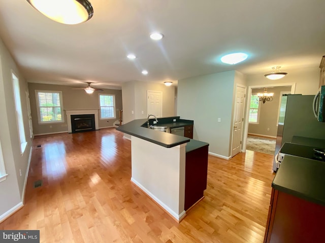 kitchen with light hardwood / wood-style flooring, sink, ceiling fan with notable chandelier, and kitchen peninsula