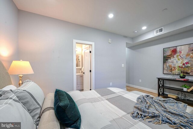 bedroom with ensuite bathroom and light wood-type flooring