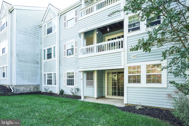 rear view of property featuring a balcony and a lawn