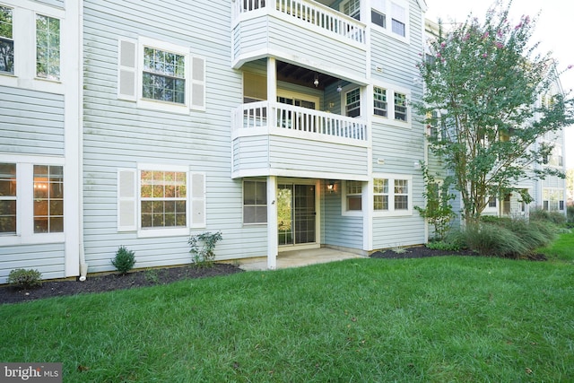 back of property with a balcony and a lawn