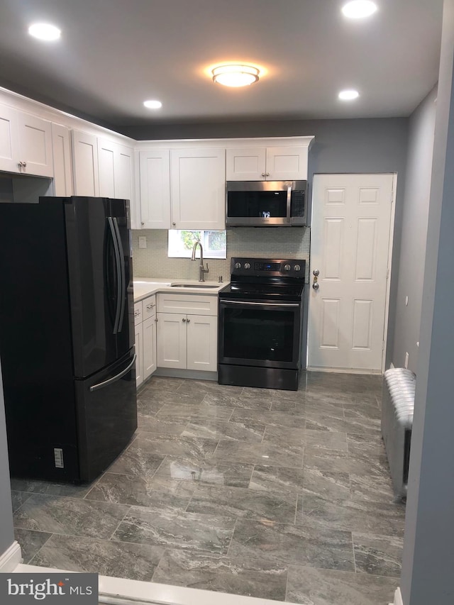 kitchen featuring white cabinetry, sink, backsplash, electric stove, and black refrigerator