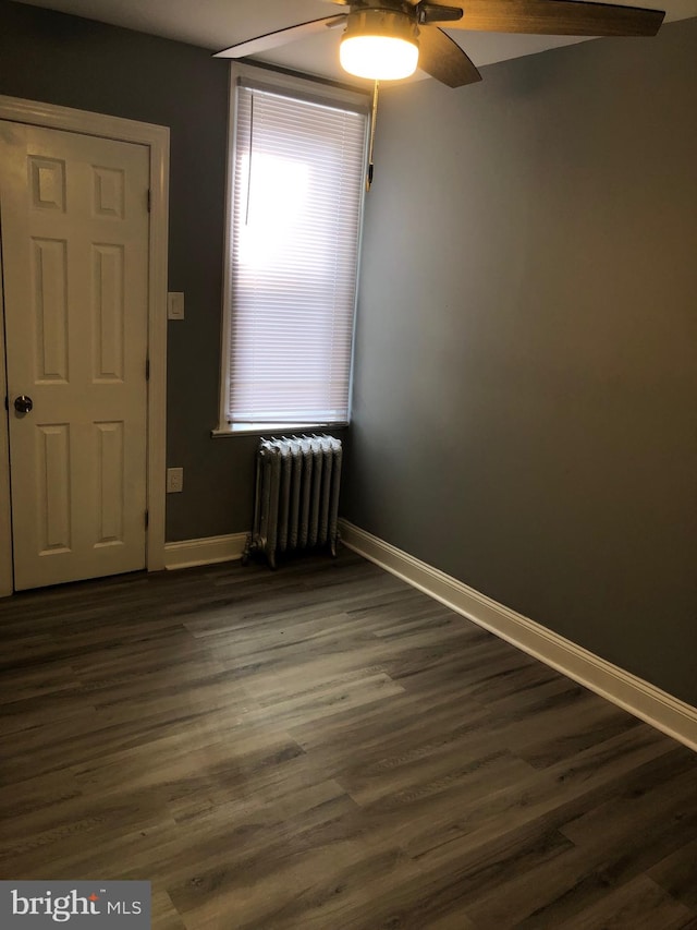 empty room featuring radiator heating unit, dark hardwood / wood-style flooring, and ceiling fan