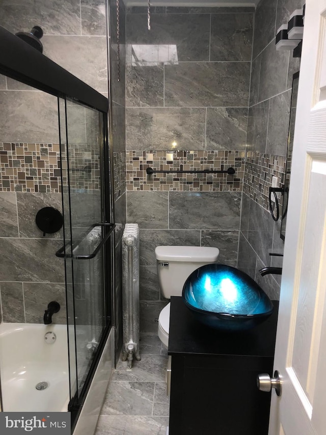 full bathroom with vanity, toilet, tile walls, and enclosed tub / shower combo