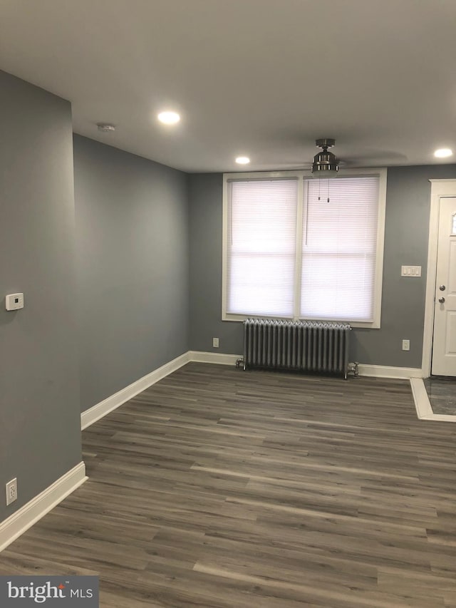 empty room with radiator and dark hardwood / wood-style floors