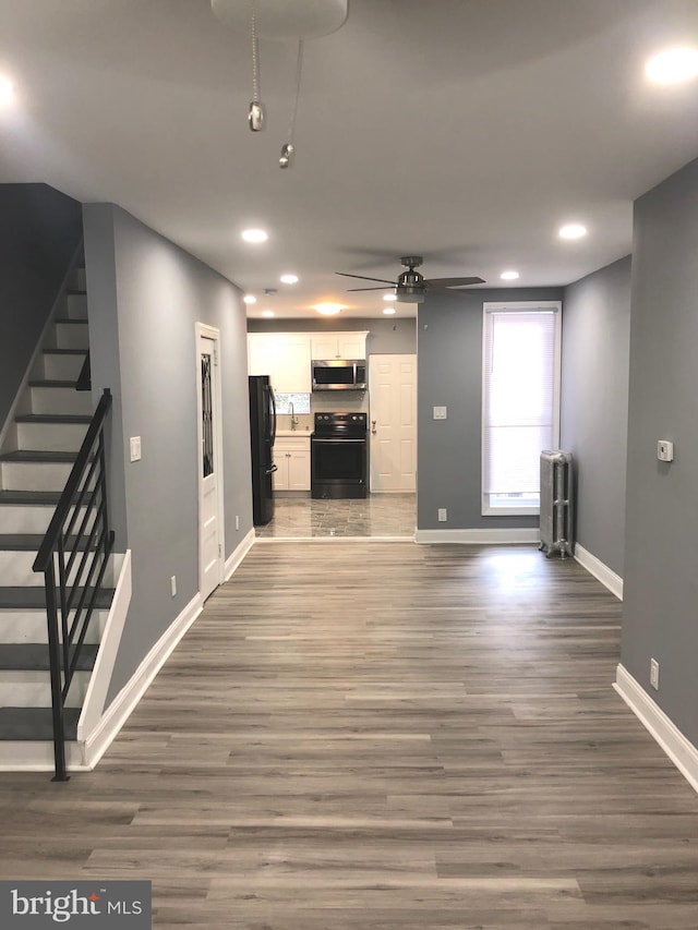 unfurnished living room featuring ceiling fan, radiator heating unit, and dark wood-type flooring