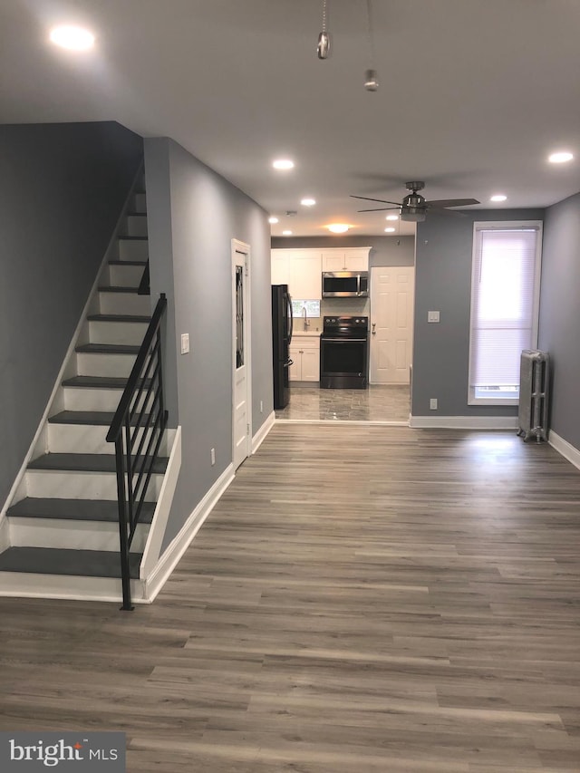 unfurnished living room with ceiling fan, dark hardwood / wood-style flooring, and radiator