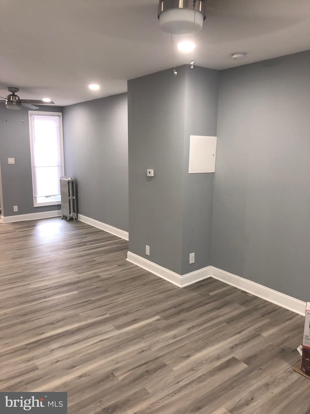 unfurnished room featuring radiator heating unit, dark hardwood / wood-style floors, and ceiling fan