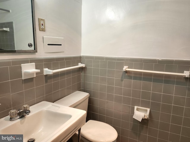 bathroom featuring sink, tile walls, and toilet