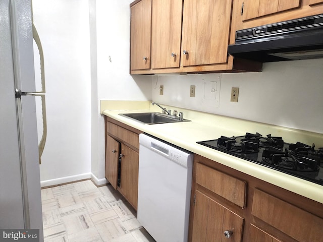 kitchen with white appliances, range hood, and sink