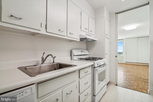 kitchen with light parquet floors, white appliances, white cabinetry, and sink