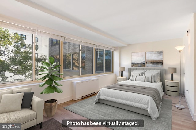 bedroom with radiator heating unit and light hardwood / wood-style floors