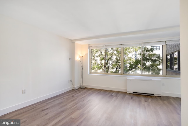 unfurnished room with radiator heating unit and light wood-type flooring