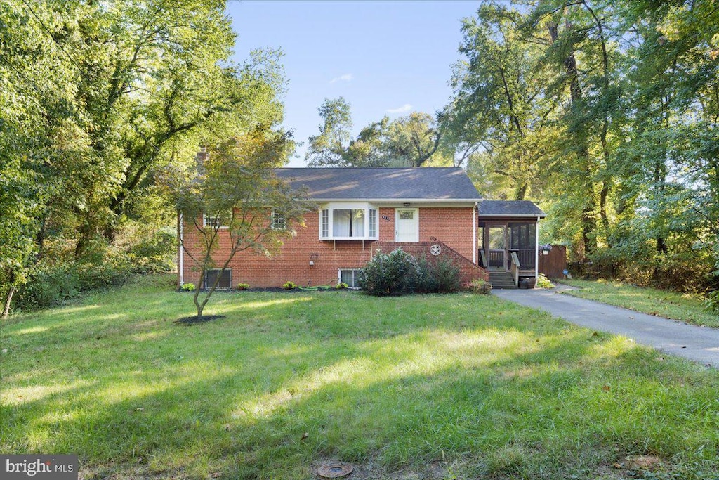 view of front facade featuring central AC unit, a sunroom, and a front lawn