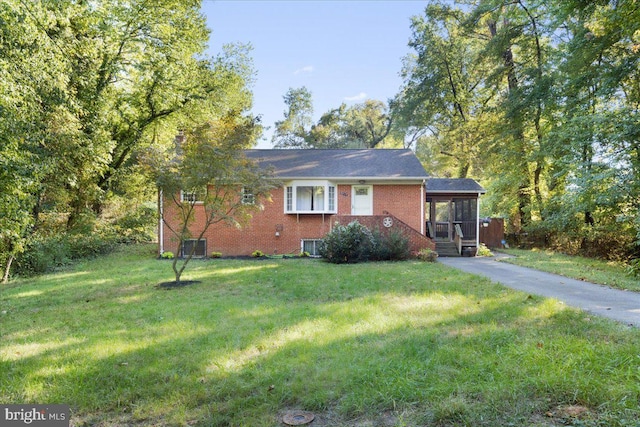 view of front facade featuring central AC unit, a sunroom, and a front lawn