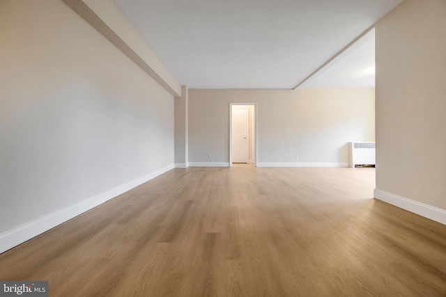 empty room featuring radiator heating unit and light wood-type flooring