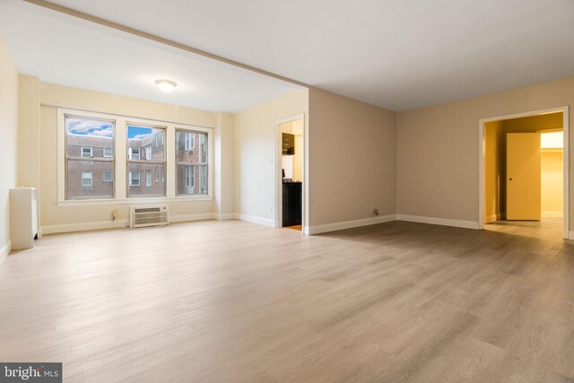 unfurnished living room with a wall mounted AC and light hardwood / wood-style flooring