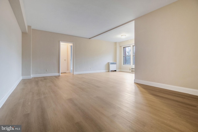 empty room with radiator heating unit and light hardwood / wood-style floors