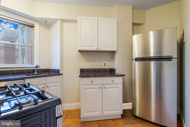 kitchen featuring appliances with stainless steel finishes, light tile patterned flooring, sink, and white cabinets