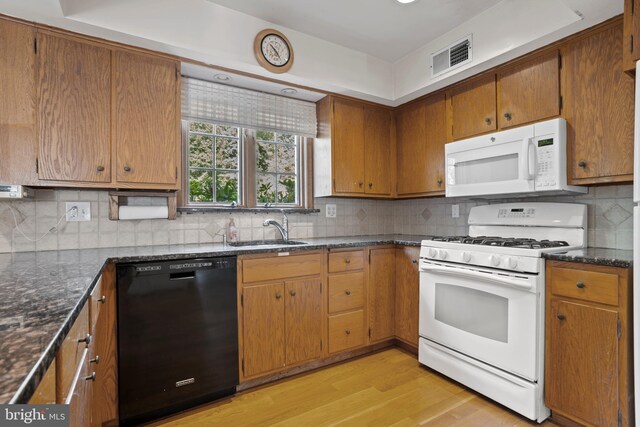 kitchen featuring sink, light hardwood / wood-style floors, white appliances, and tasteful backsplash