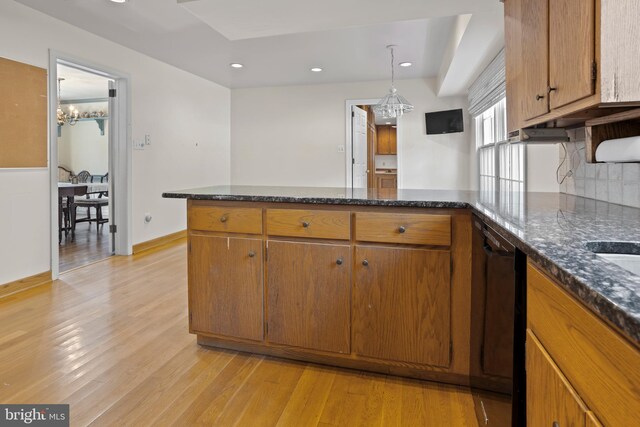 kitchen featuring a notable chandelier, black dishwasher, light hardwood / wood-style flooring, and kitchen peninsula