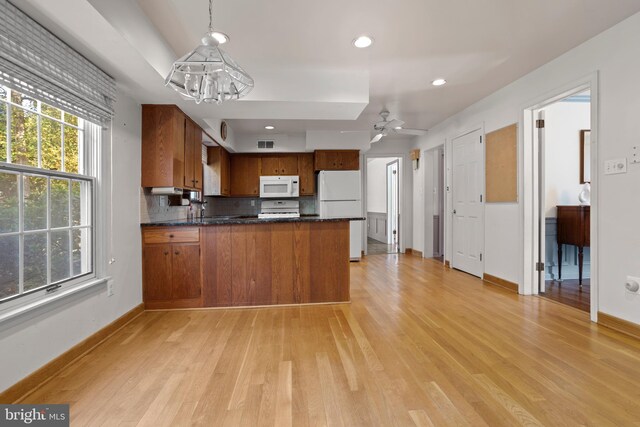 kitchen featuring kitchen peninsula, white appliances, decorative light fixtures, and light hardwood / wood-style floors