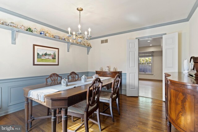 dining space with dark hardwood / wood-style floors, ornamental molding, and a chandelier