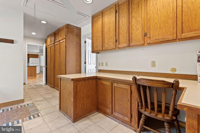 kitchen featuring kitchen peninsula, white fridge, and light tile patterned floors