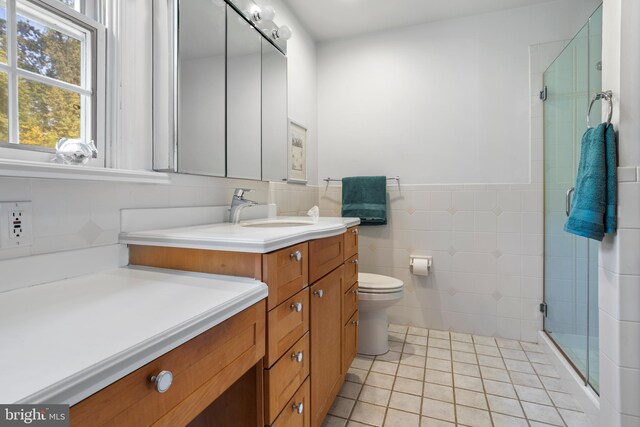 bathroom with vanity, tile patterned floors, walk in shower, tile walls, and toilet