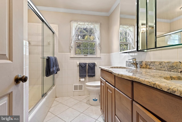 full bathroom with shower / bath combination with glass door, vanity, tile walls, and toilet