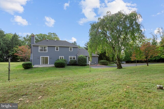 rear view of house with a patio and a lawn