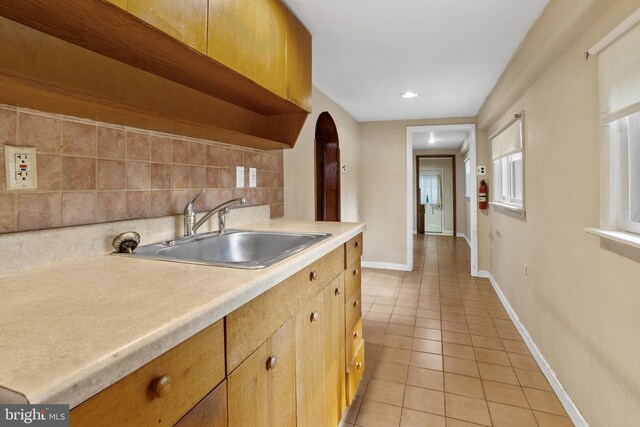 kitchen featuring light tile patterned flooring, decorative backsplash, and sink