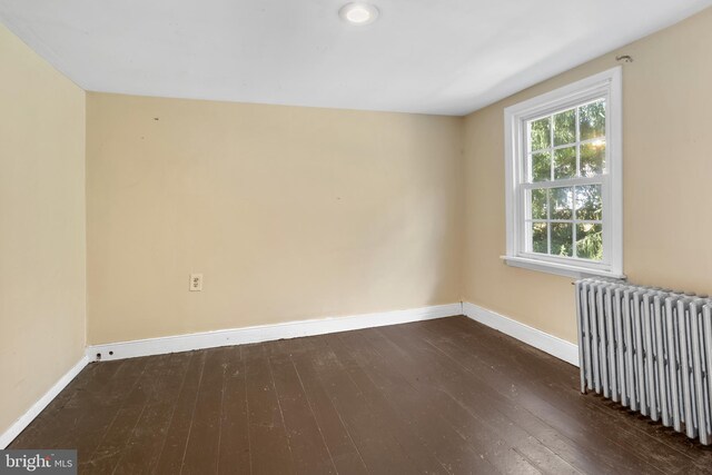 spare room featuring dark hardwood / wood-style floors and radiator