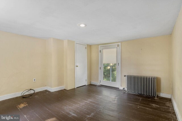 spare room with dark wood-type flooring and radiator heating unit