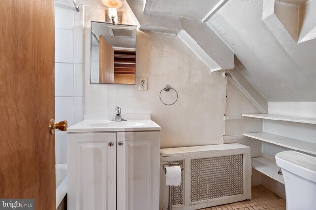 bathroom featuring vaulted ceiling, vanity, tile patterned flooring, and toilet