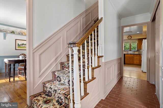 staircase featuring ornamental molding, sink, and hardwood / wood-style floors