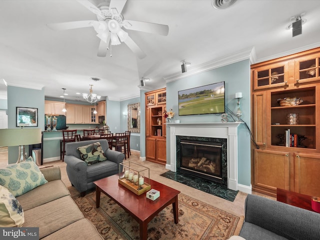 living room with ornamental molding, a high end fireplace, and ceiling fan with notable chandelier