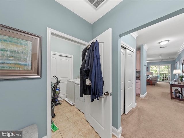 clothes washing area featuring light carpet, washer and dryer, and crown molding