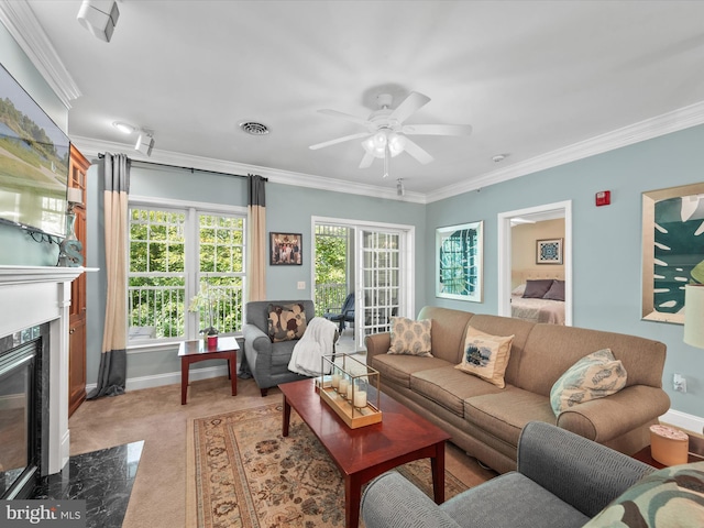 carpeted living room with ornamental molding, a high end fireplace, and ceiling fan