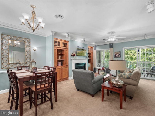 carpeted dining area with ceiling fan with notable chandelier and crown molding