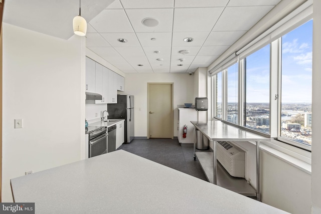 kitchen with a drop ceiling, decorative light fixtures, sink, white cabinets, and appliances with stainless steel finishes