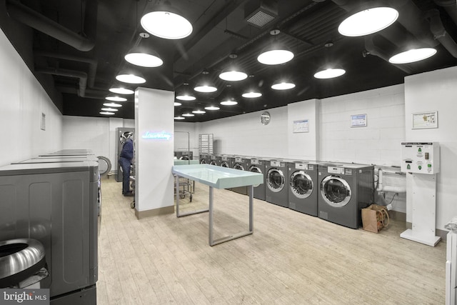 laundry area featuring washing machine and dryer and light hardwood / wood-style floors