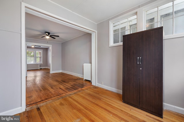 unfurnished room with ceiling fan, light hardwood / wood-style floors, and radiator heating unit