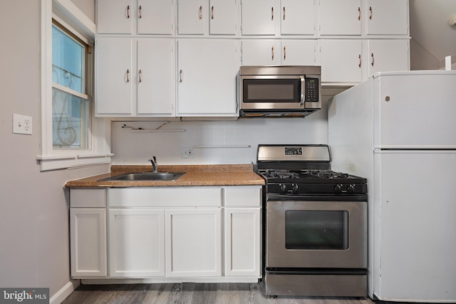 kitchen featuring dark hardwood / wood-style floors, tasteful backsplash, sink, white cabinetry, and appliances with stainless steel finishes