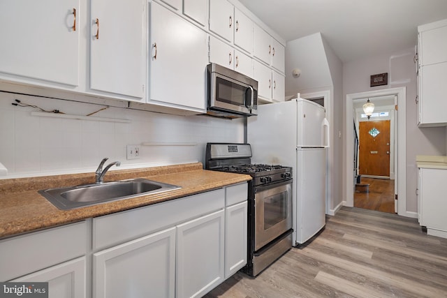 kitchen with light hardwood / wood-style flooring, appliances with stainless steel finishes, sink, and white cabinetry