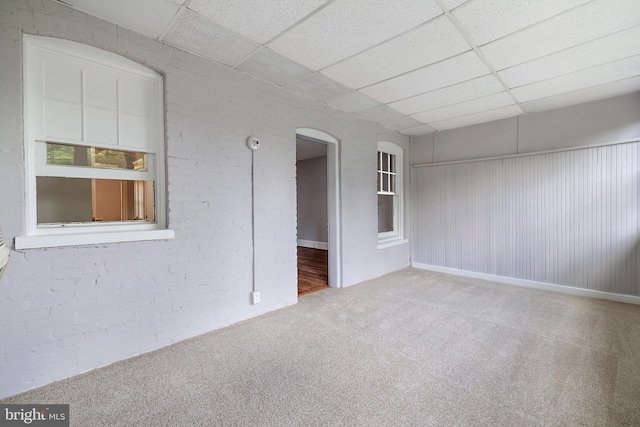 carpeted empty room featuring a paneled ceiling