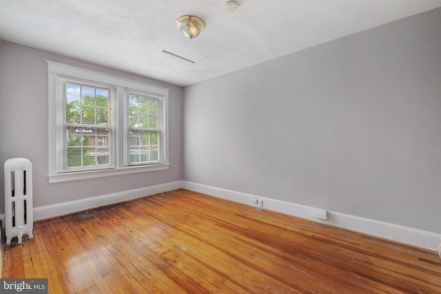 unfurnished room featuring wood-type flooring, a textured ceiling, and radiator